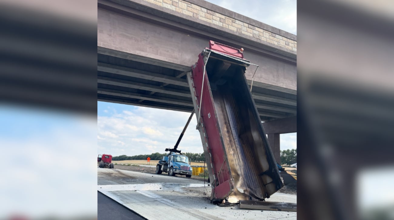 The dump truck's raised box became wedged against the overhead structure after the driver...
